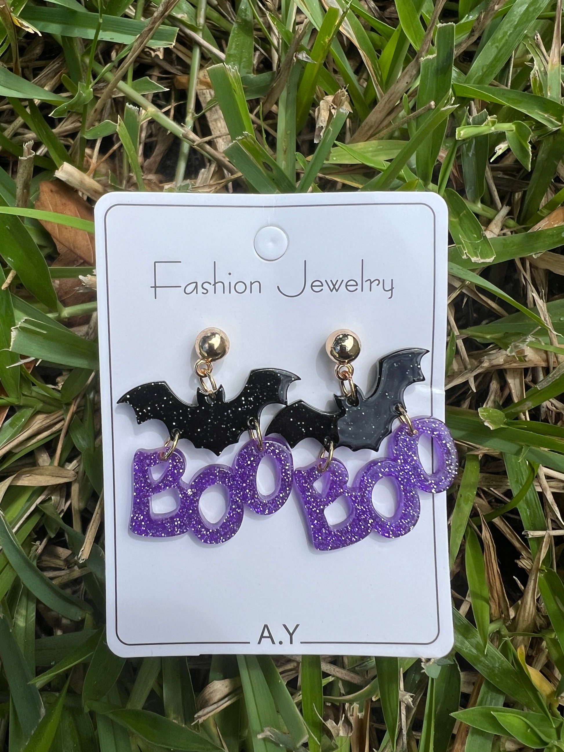 Halloween-themed earrings on a card with 'Fashion Jewelry' branding, placed on grass.