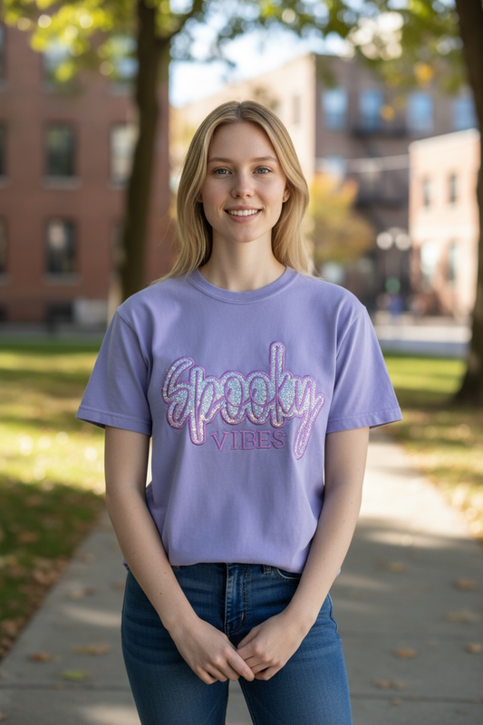 Person wearing a purple 'Spooky Vibes' t-shirt standing outdoors on a sunny day.